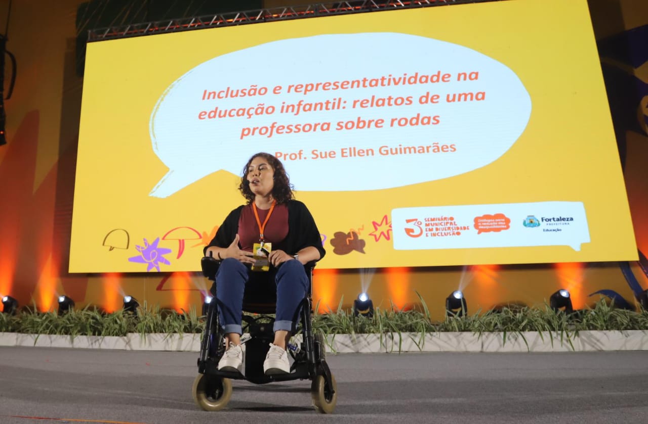 professora cadeirante fala no palco do centro de eventos